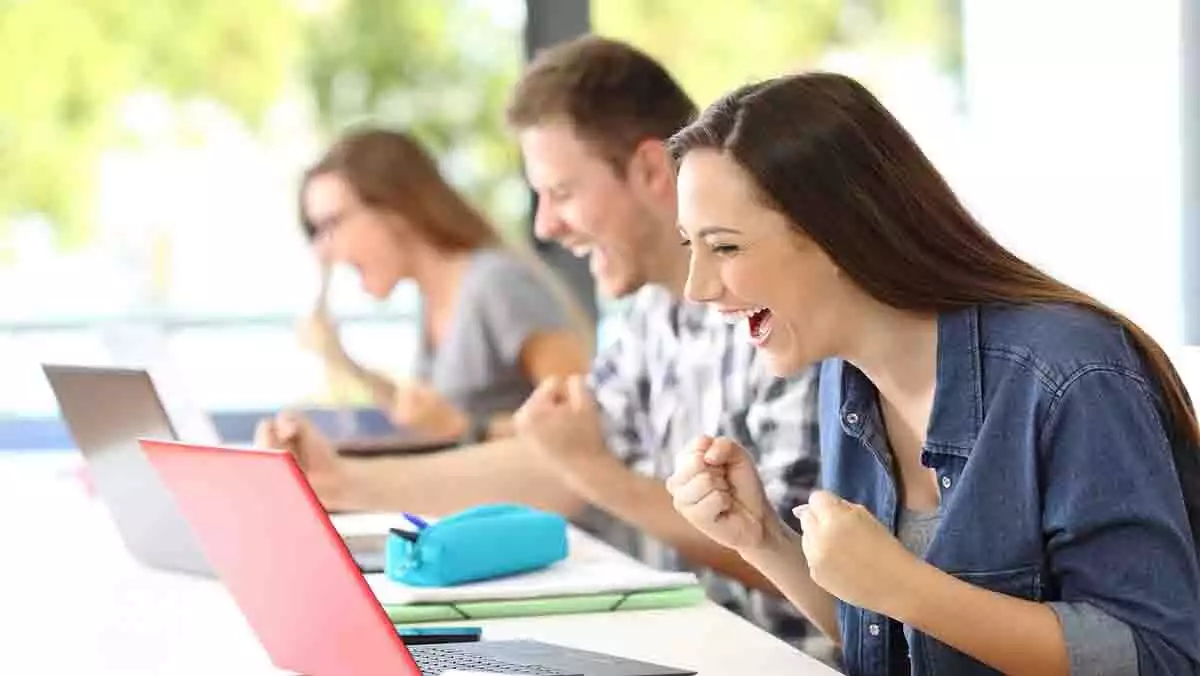 Estudiantes contentos frente a un ordenador.