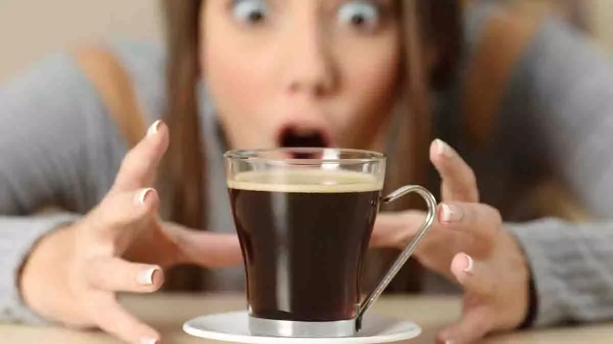 Mujer a punto de sujetar una taza de café.